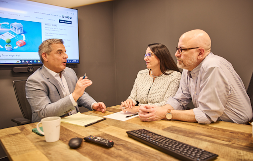An estate planning attorney meets with a couple in a conference room, discussing trust and estate planning strategies while reviewing documents together.